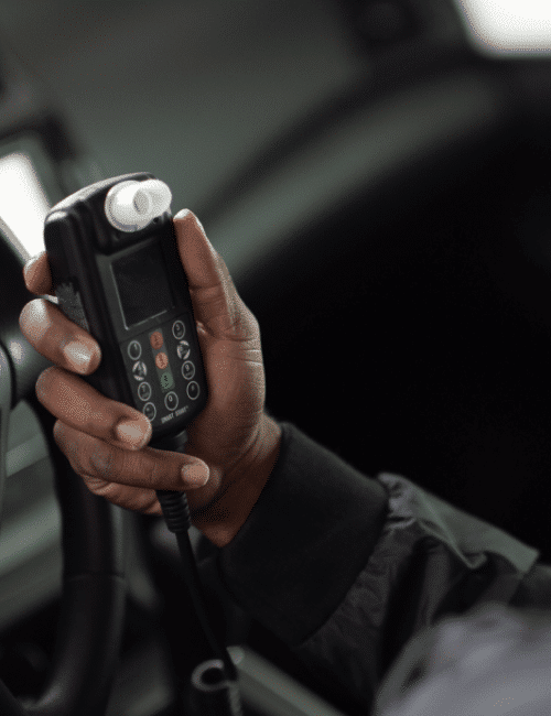 Person holding a Smart Start ignition interlock device inside a vehicle