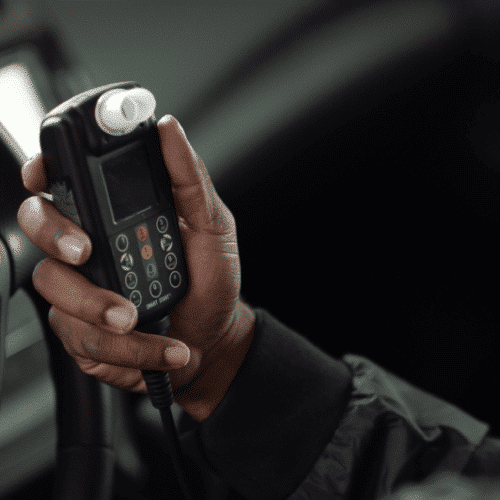 Person holding a Smart Start ignition interlock device inside a vehicle
