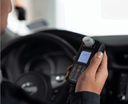 Driver holding a Smart Start 2030 ignition interlock device inside a vehicle