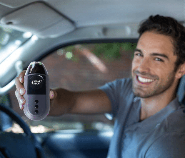 Man holding a Smart Start 3030 ignition interlock device inside a vehicle